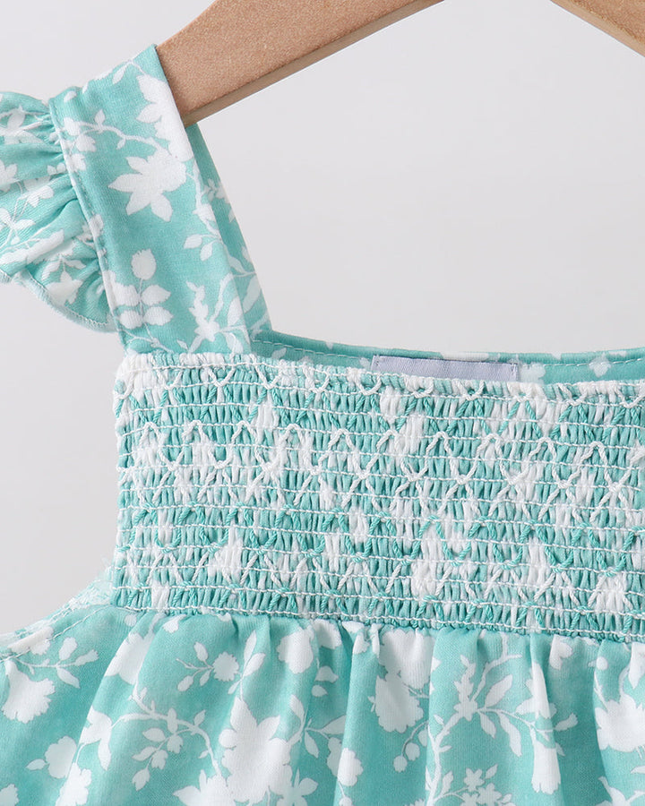 Close-up of a turquoise floral dress with smocked details on a white background