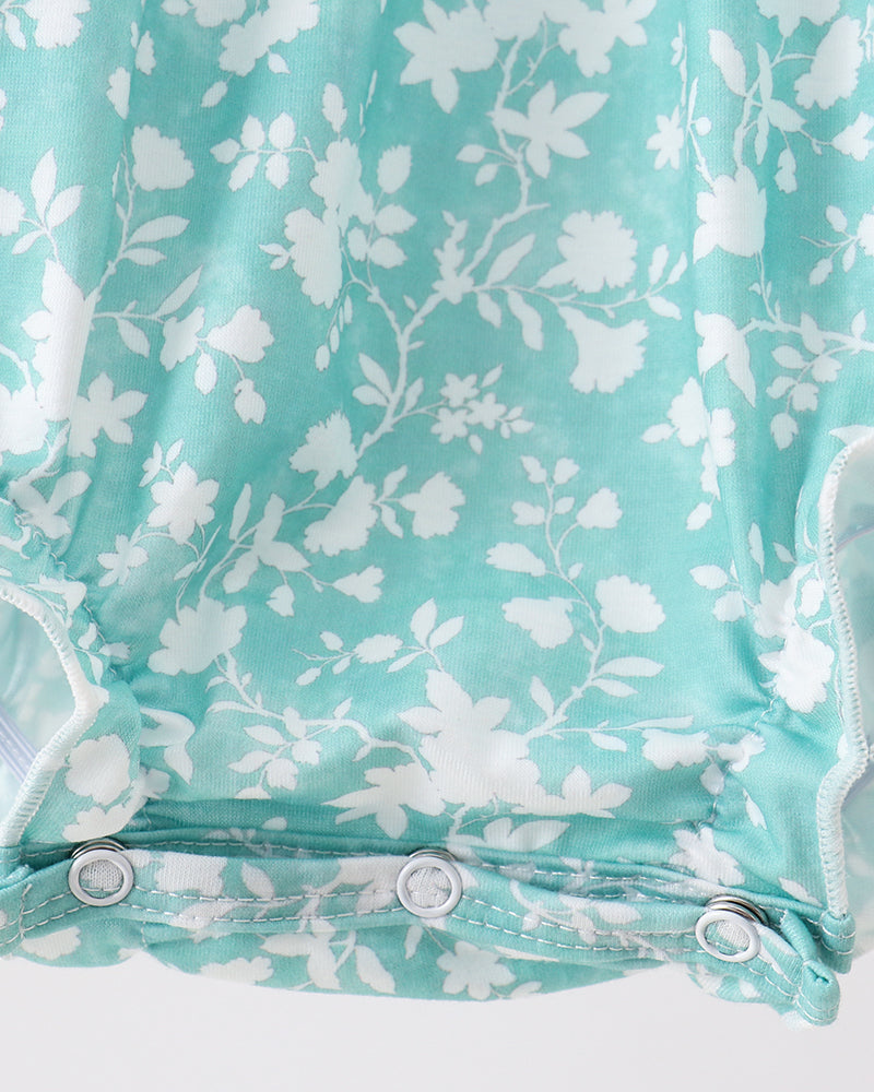 Teal baby romper with white floral pattern on a light gray background