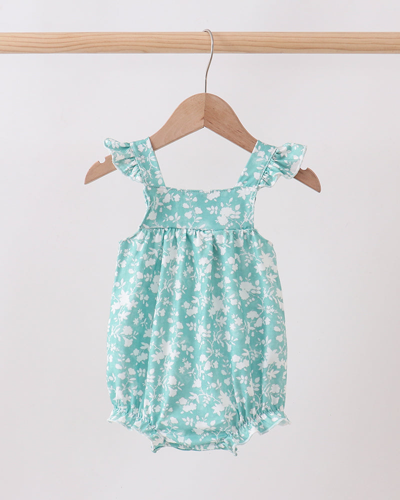 Green floral baby romper on a wooden hanger against a white background