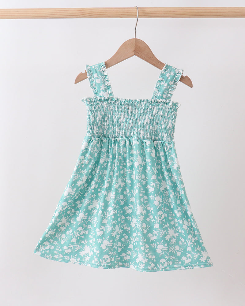 Green floral dress on a hanger against a white background