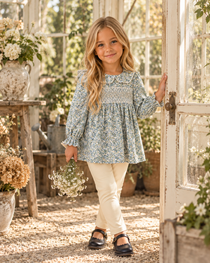 Girl wearing a floral smocked tunic top and cream leggings with long sleeves