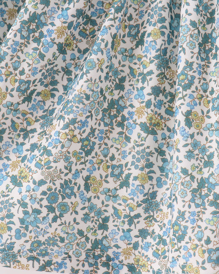 Floral print fabric close-up with blue, green, and yellow flowers on a light background