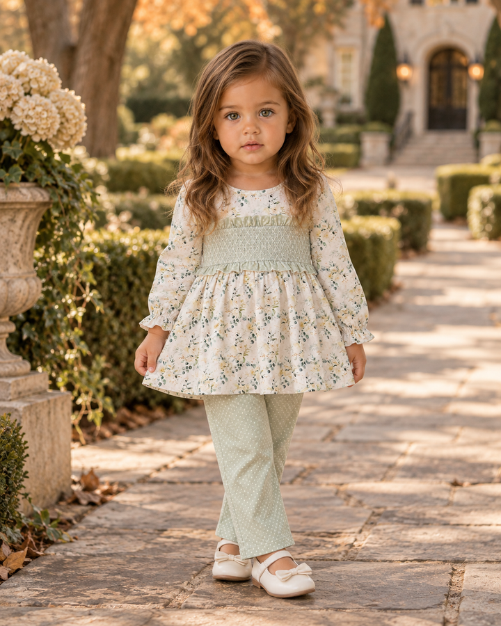 Child wearing white floral ruffle tunic and sage green dotted leggings