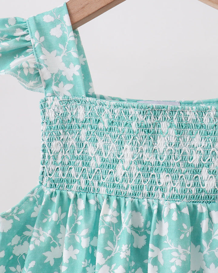Close-up of a turquoise floral dress with smocked waistband on a white background