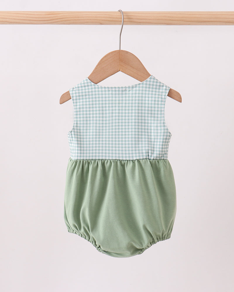Green checkered baby romper on a wooden hanger against a white background