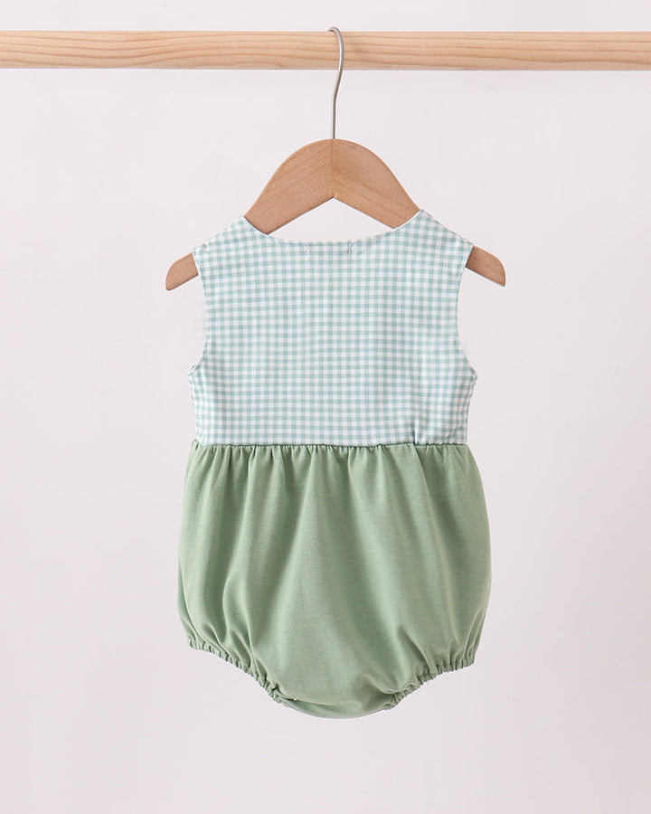 Green checkered baby romper on a wooden hanger against a white background