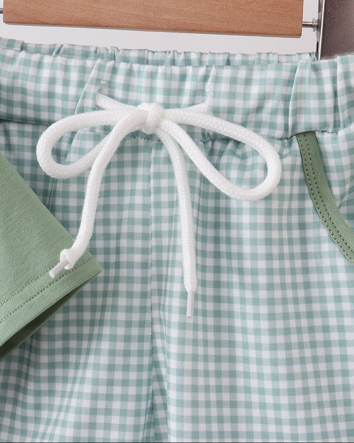Green and white checkered shorts with a drawstring on a hanger.