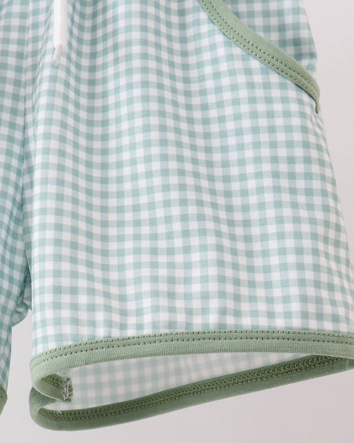 Green and white checkered fabric with a visible seam on a light gray background