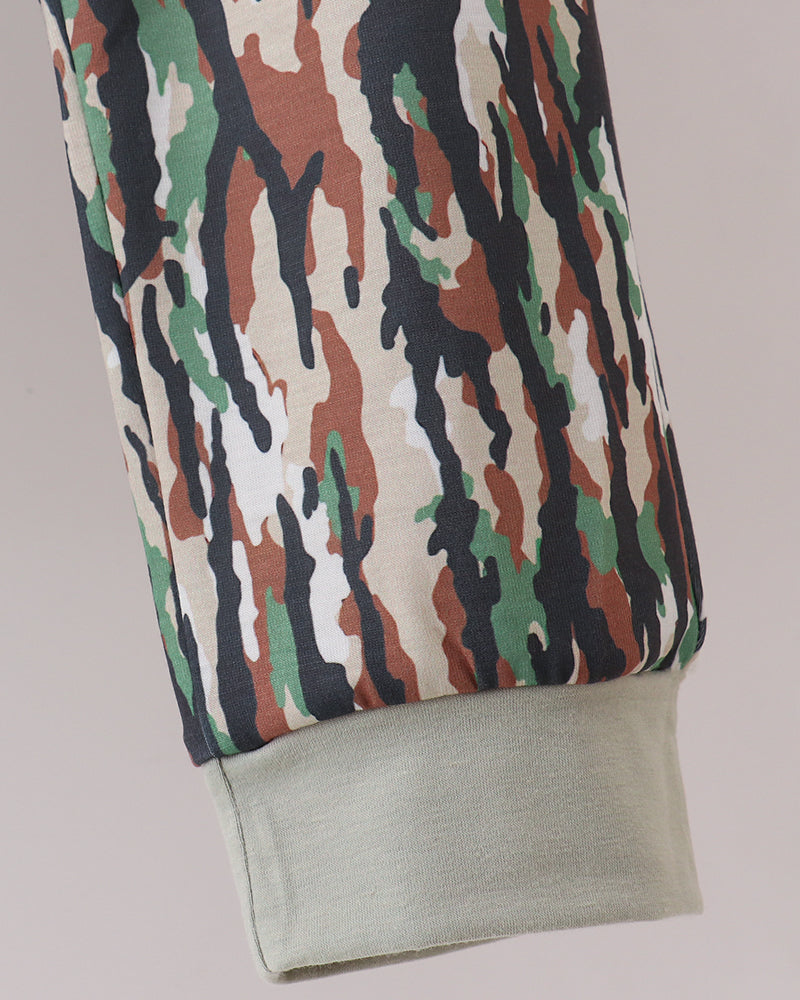 Close-up of a camouflage-patterned sleeve with a light sage green ribbed cuff, shown against a solid light gray background.