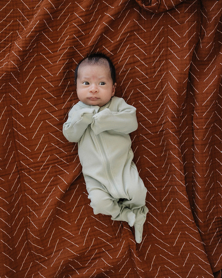 Sage green zip-front footed romper on baby with long sleeves and ribbed fabric
