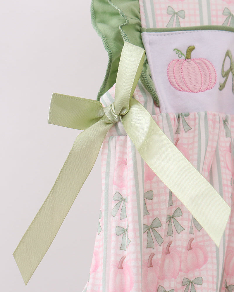 Baby dress detail with green ruffle trim and long pastel bows at the back