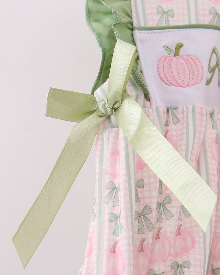 Baby dress detail with green ruffle trim and long pastel bows at the back