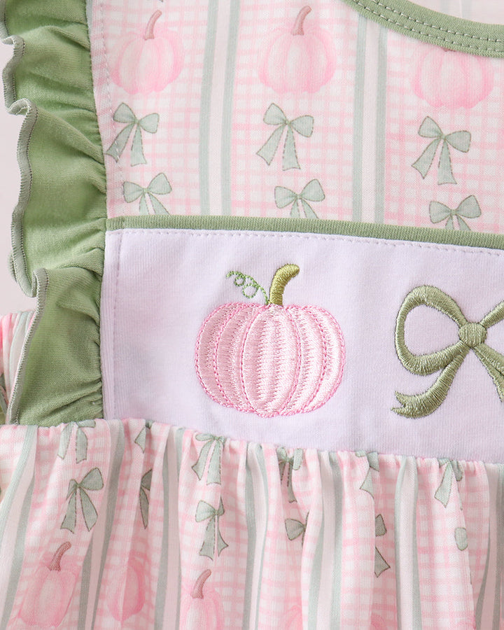 Pink dress front panel with pumpkin embroidery, bow detail, and sage ruffle trim