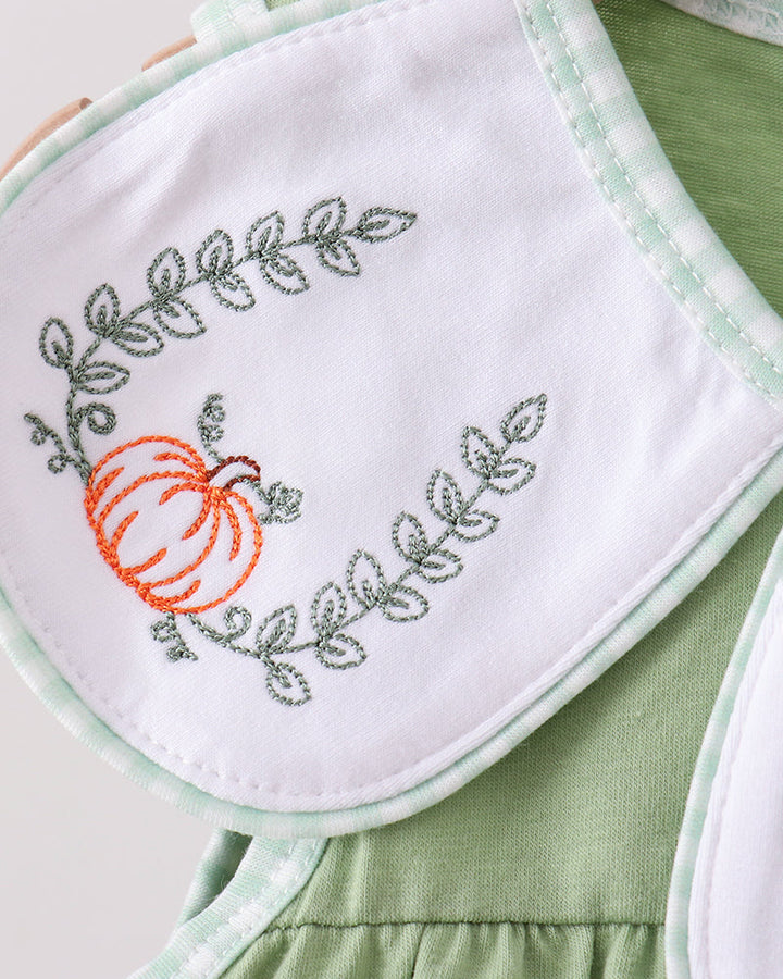 White bib with pumpkin embroidery and green stitching on mint-trimmed sleeveless dress