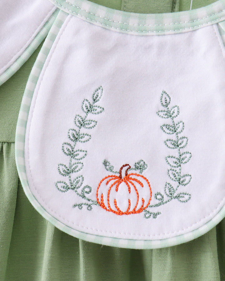 White bib-style panel with orange pumpkin and green leafy embroidery on green romper