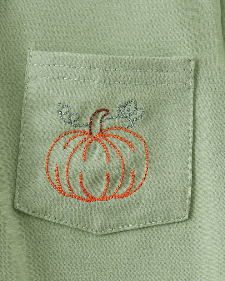 Sage green chest pocket with stitched pumpkin embroidery in orange and blue
