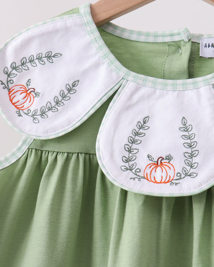 Green dress with two white embroidered bibs showing pumpkin and leaf wreaths
