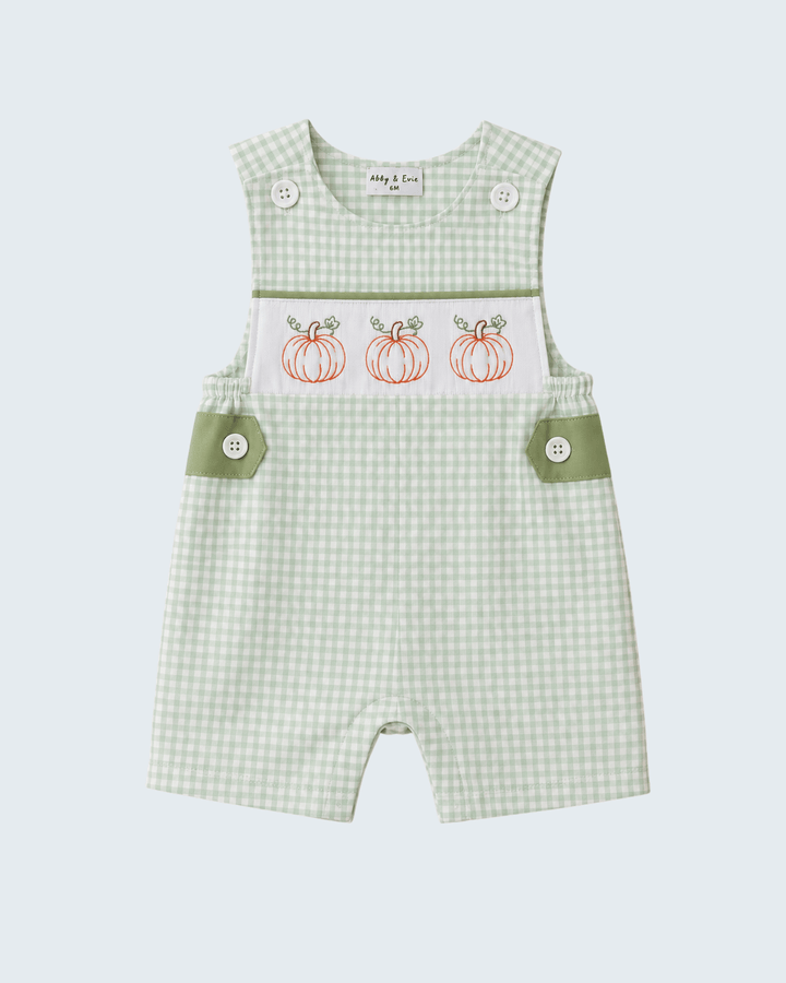 A baby romper in a light green and white gingham pattern, featuring a white chest panel with three embroidered orange pumpkins and sage green side pocket flaps with snap buttons.