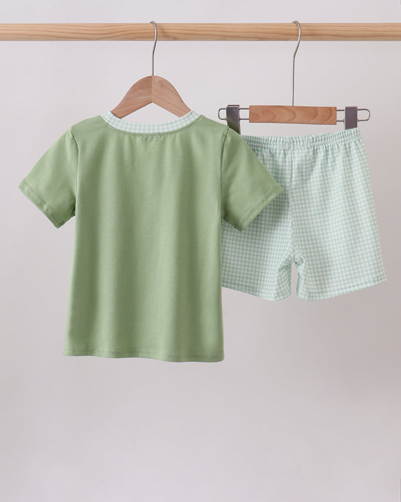 Sage green baby T-shirt and gingham shorts set, both on hangers