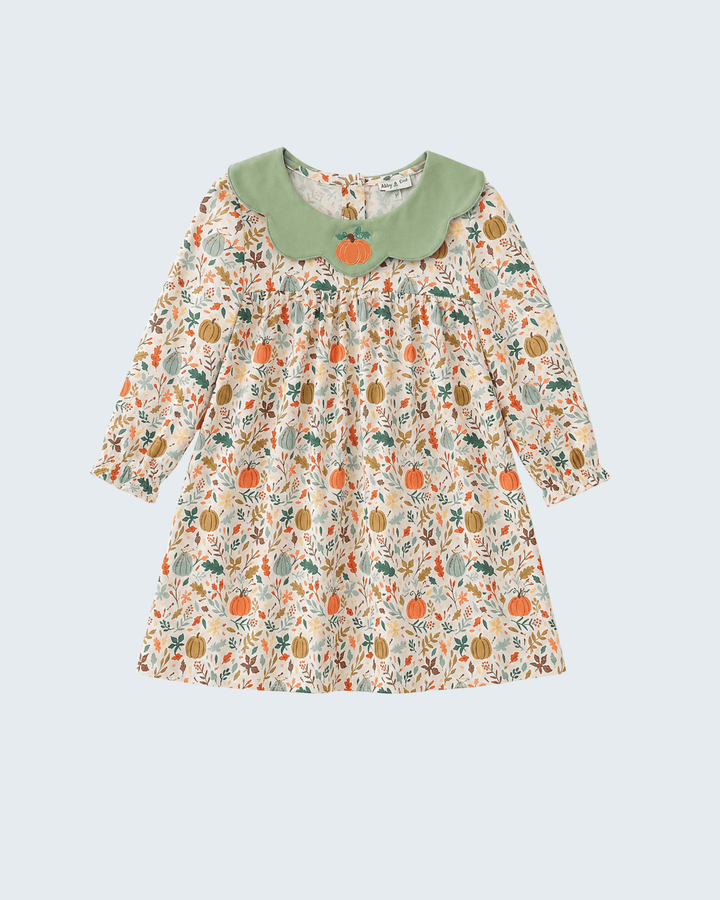 A long-sleeve toddler dress with an autumn-themed pumpkin and leaf print on a cream background, featuring a solid sage green Peter Pan collar with a small orange pumpkin applique at the center.