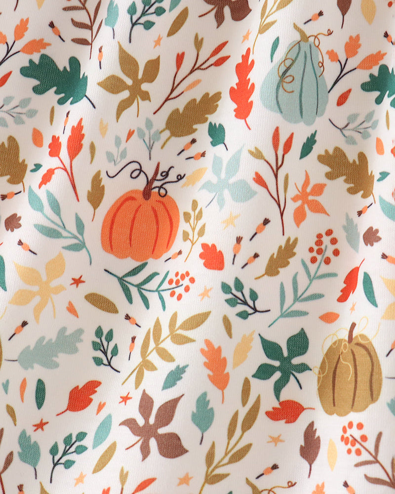 A close-up of a fabric with an all-over autumn pattern featuring pumpkins, leaves, and berries in orange, teal, brown, and beige on an off-white background.
