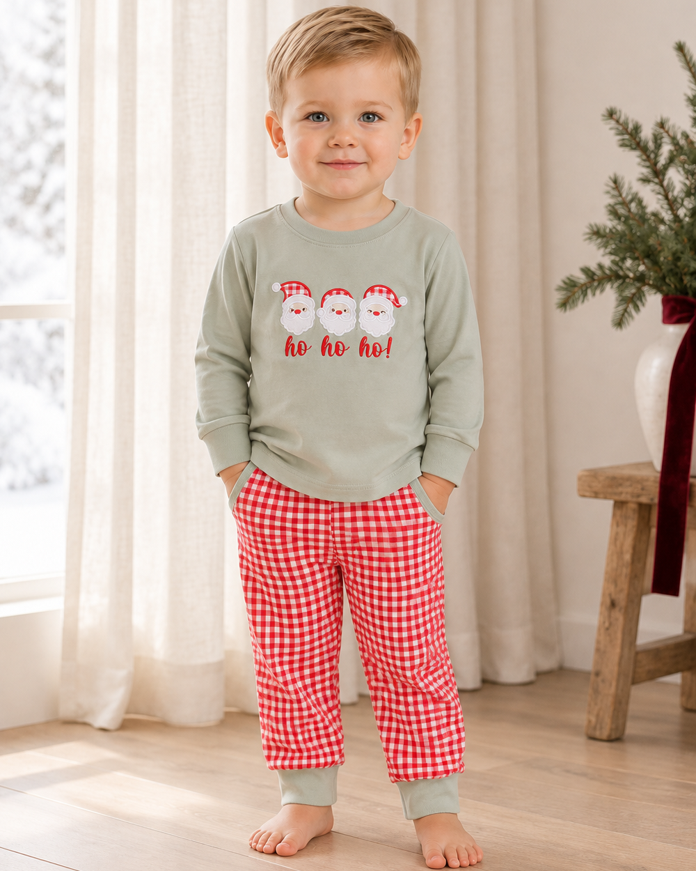 Child wearing sage long-sleeve Santa shirt and red gingham pants