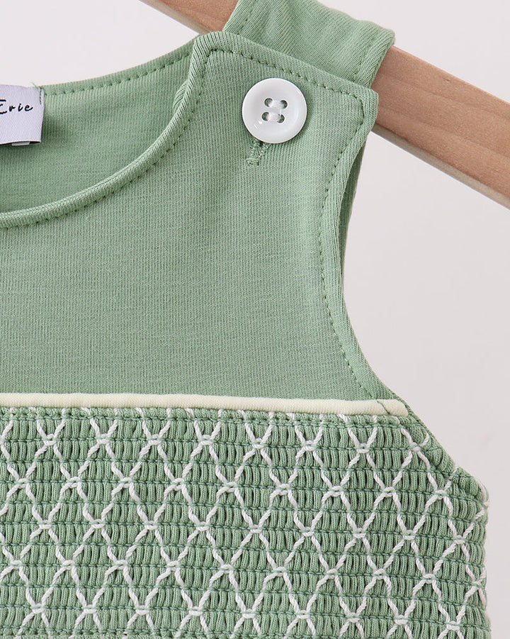 Sage green jon jon close-up: buttoned shoulder and white smocked yoke trim