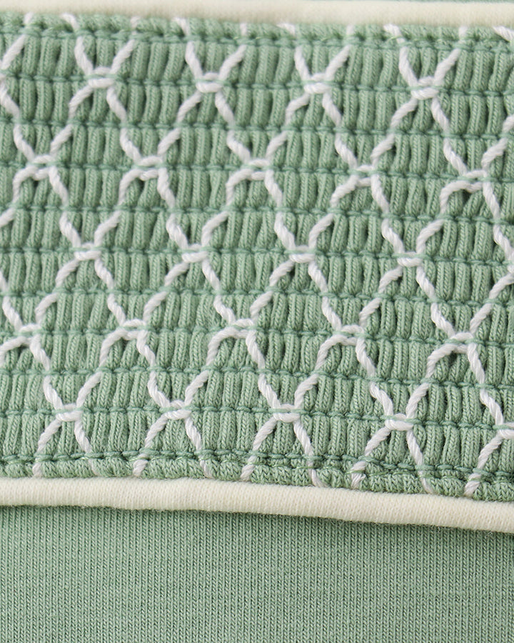 Smocked yoke panel on sage green jon jon with white embroidered net pattern