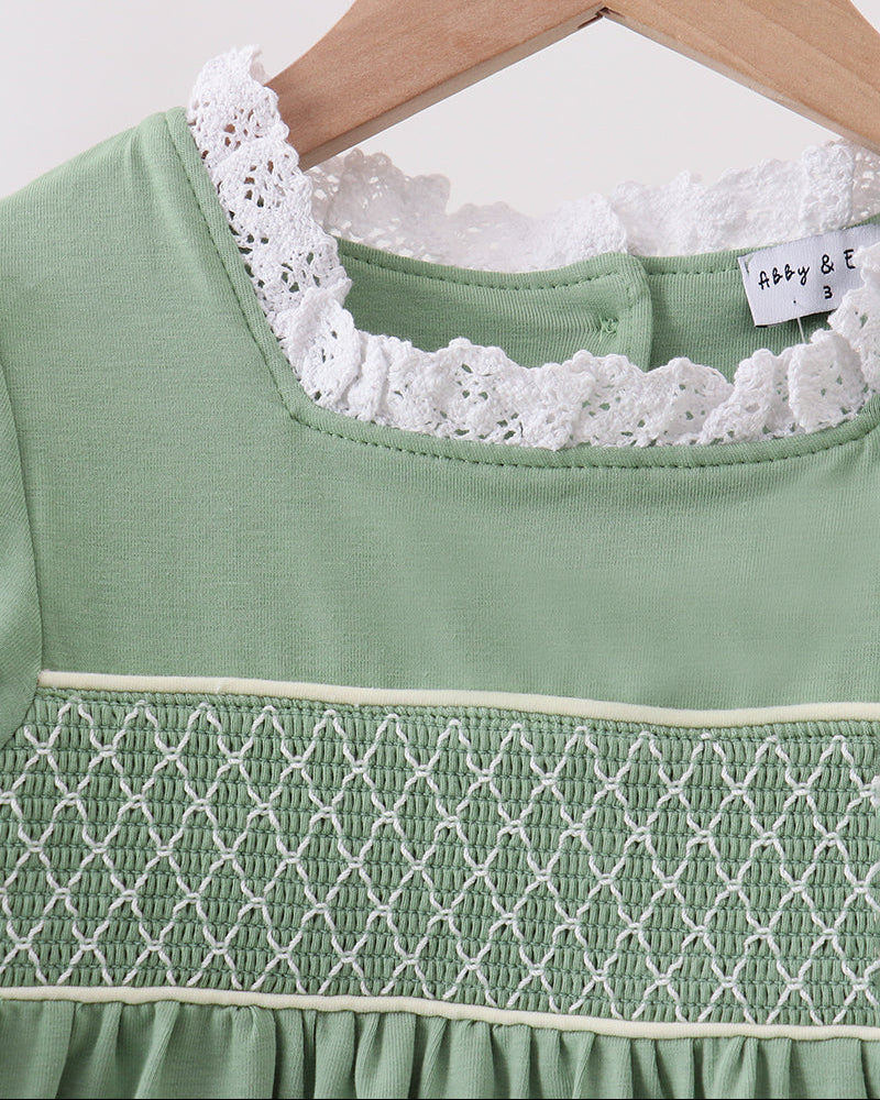 Sage green dress neckline with white lace trim and smocked yoke detail, close-up