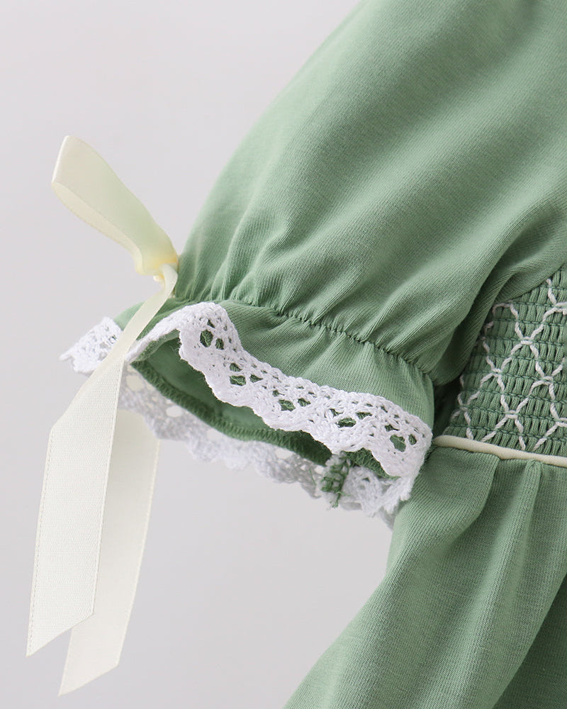 Sage green bloomers with white lace panel and bow ties at the leg opening, close-up