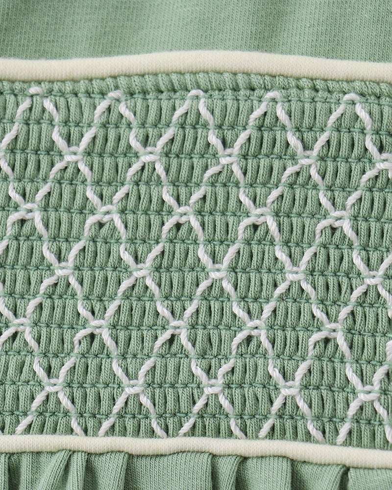 Sage green smocked lace panel on toddler bloomer waistband, tight close-up