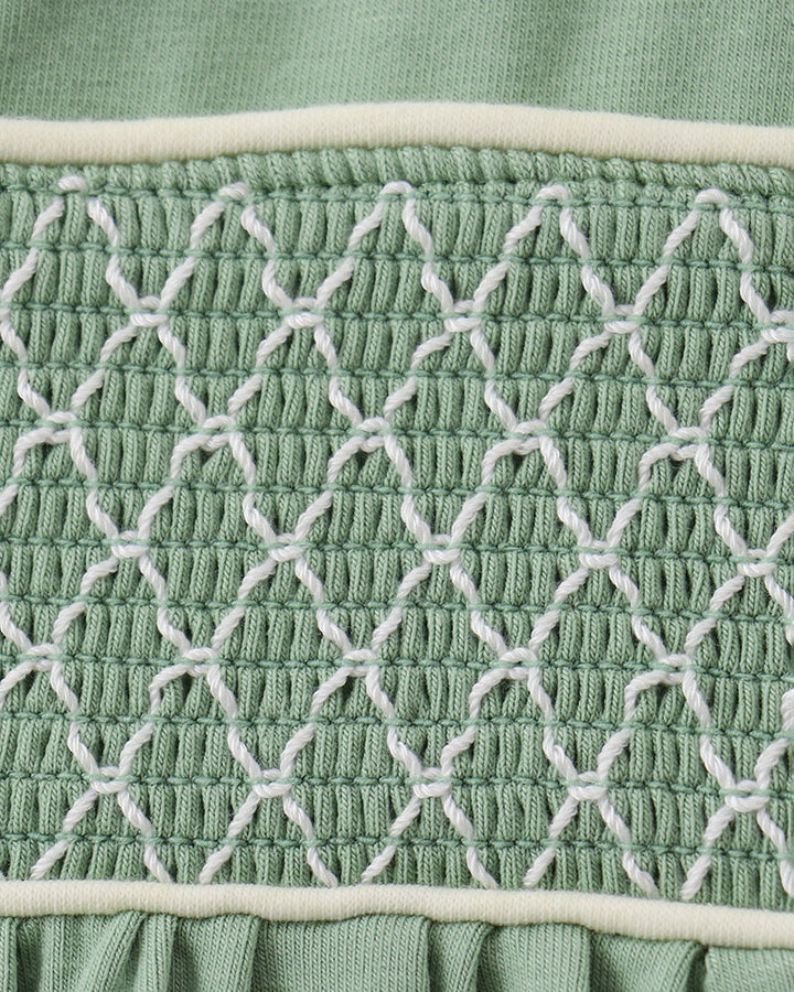 Sage green smocked lace panel on toddler bloomer waistband, tight close-up