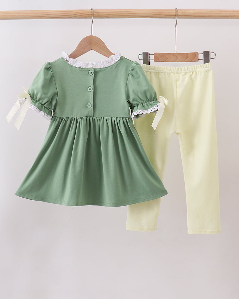 Sage green button-front smocked top with lace cuffs and pale yellow pants