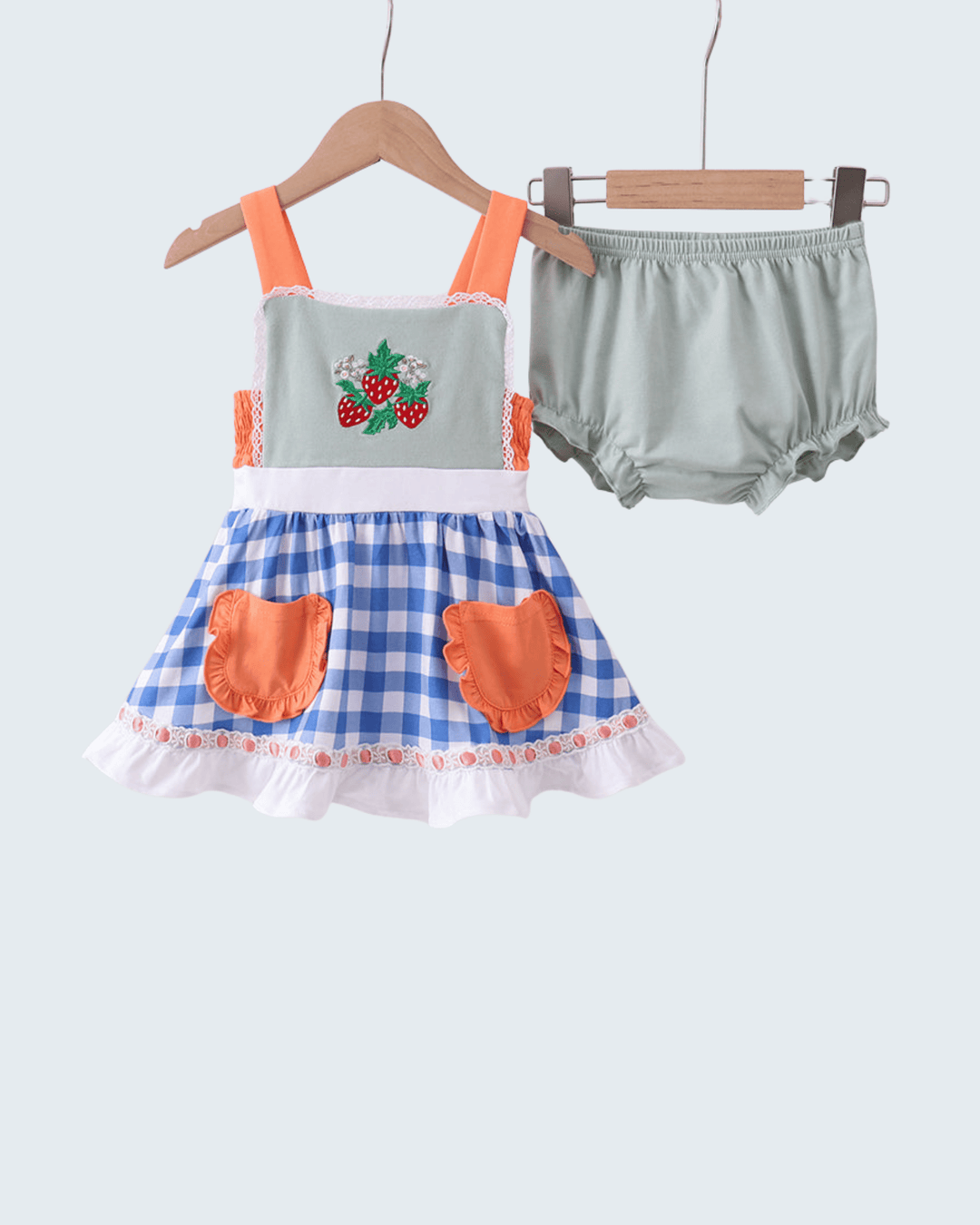 Children's outfit with checkered dress and bloomers on hangers against a white background