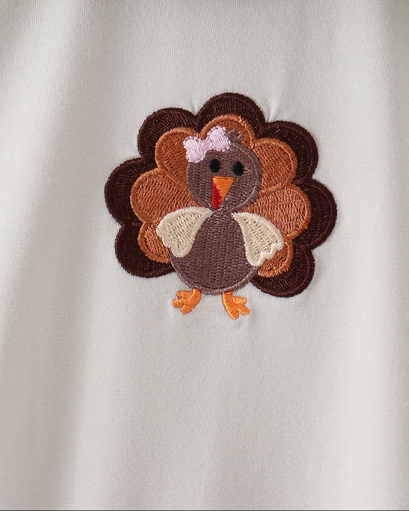 Off-white romper with large embroidered turkey applique on the chest