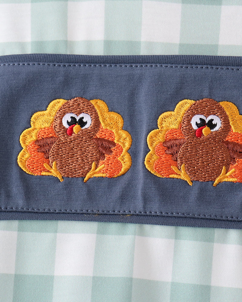 Embroidered turkey face patches on navy trim of gingham long-sleeve top