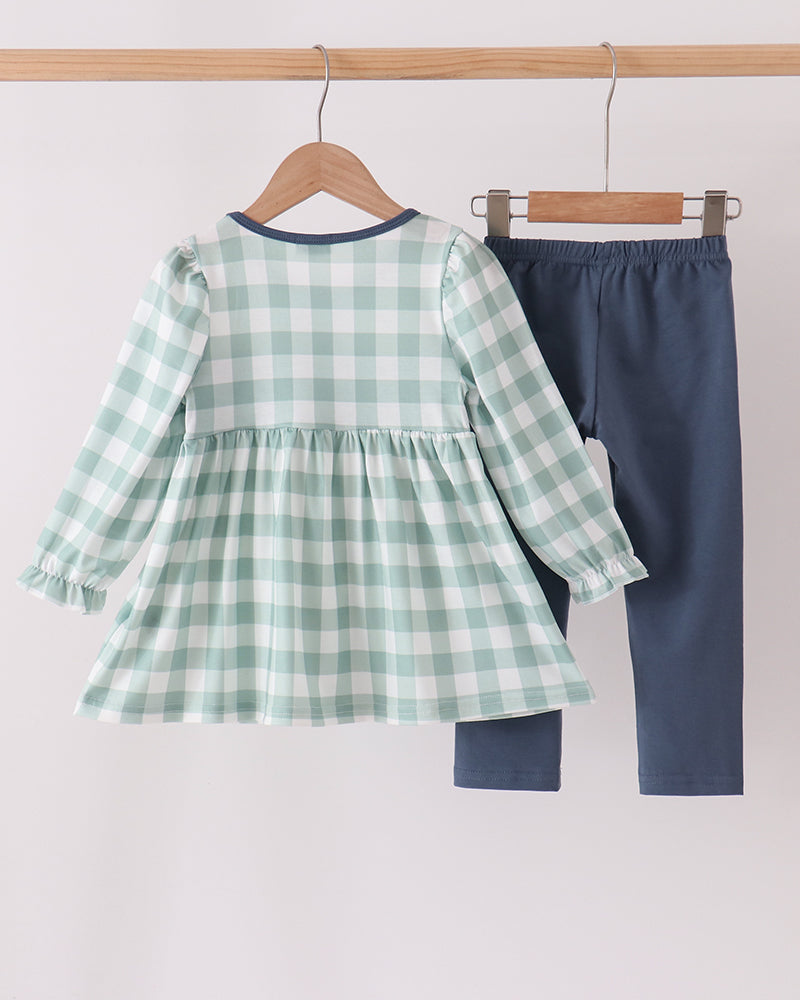 Sage green gingham dress and navy pants set hanging on wooden hangers