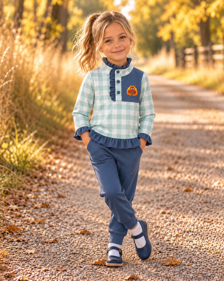 Young girl is wearing a Sage Turkey Embroidered Gingham Ruffle Jogger Set
