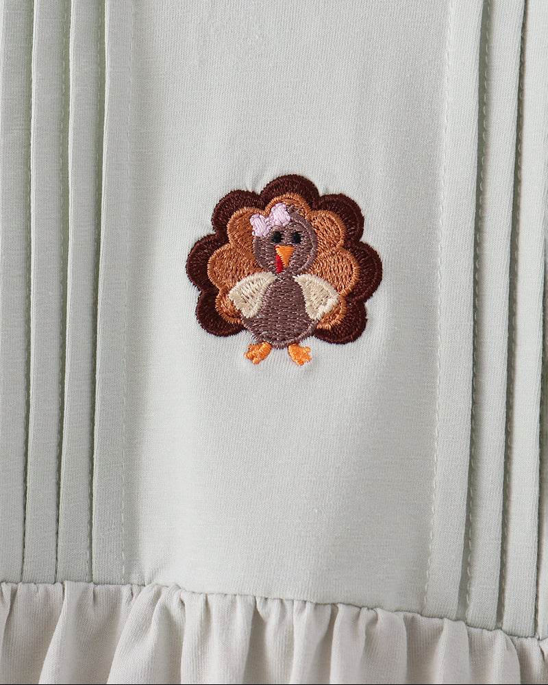Sage ruffle top with turkey embroidery on chest, close-up