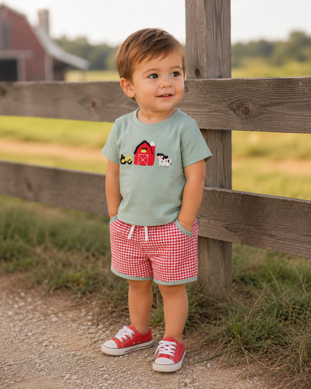 Toddler boy standing in front of a wooden fence