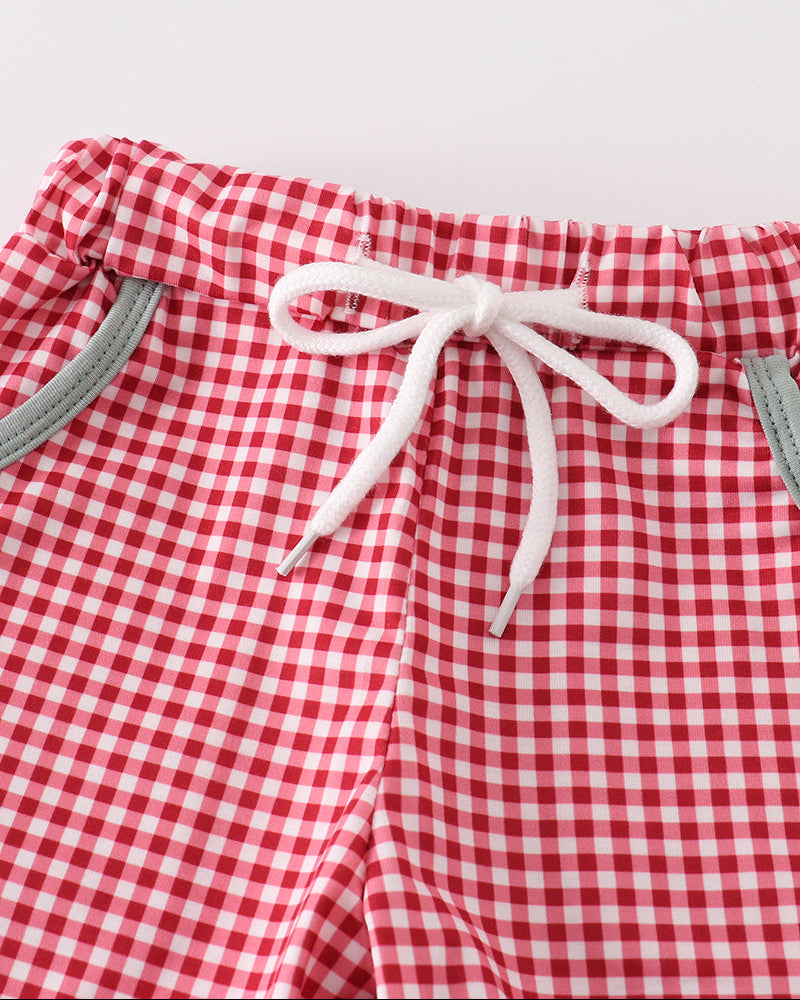 Red and white gingham checkered shorts with a white drawstring bow at the waist and gray side pockets, shown against a plain light background.