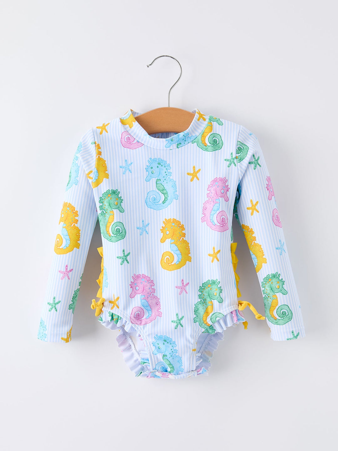 Baby swimsuit with seahorse and starfish pattern on a hanger against a white background