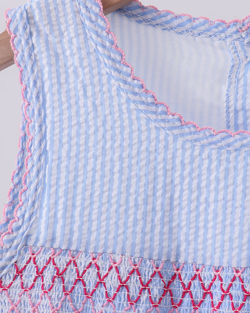 Close-up of a blue and white checkered fabric with pink stitching on a plain background