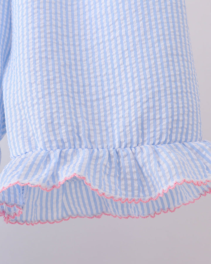 Close-up of a blue and white checkered dress with pink trim on a light gray background