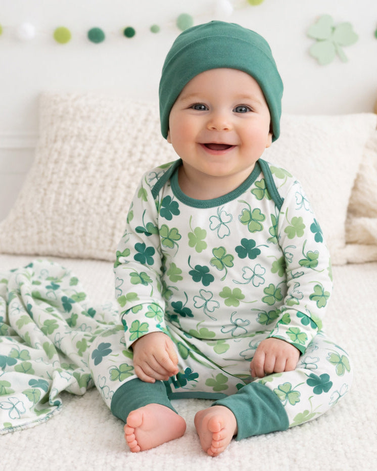 Baby wearing bamboo romper with green clover print, long sleeves and footed fit.