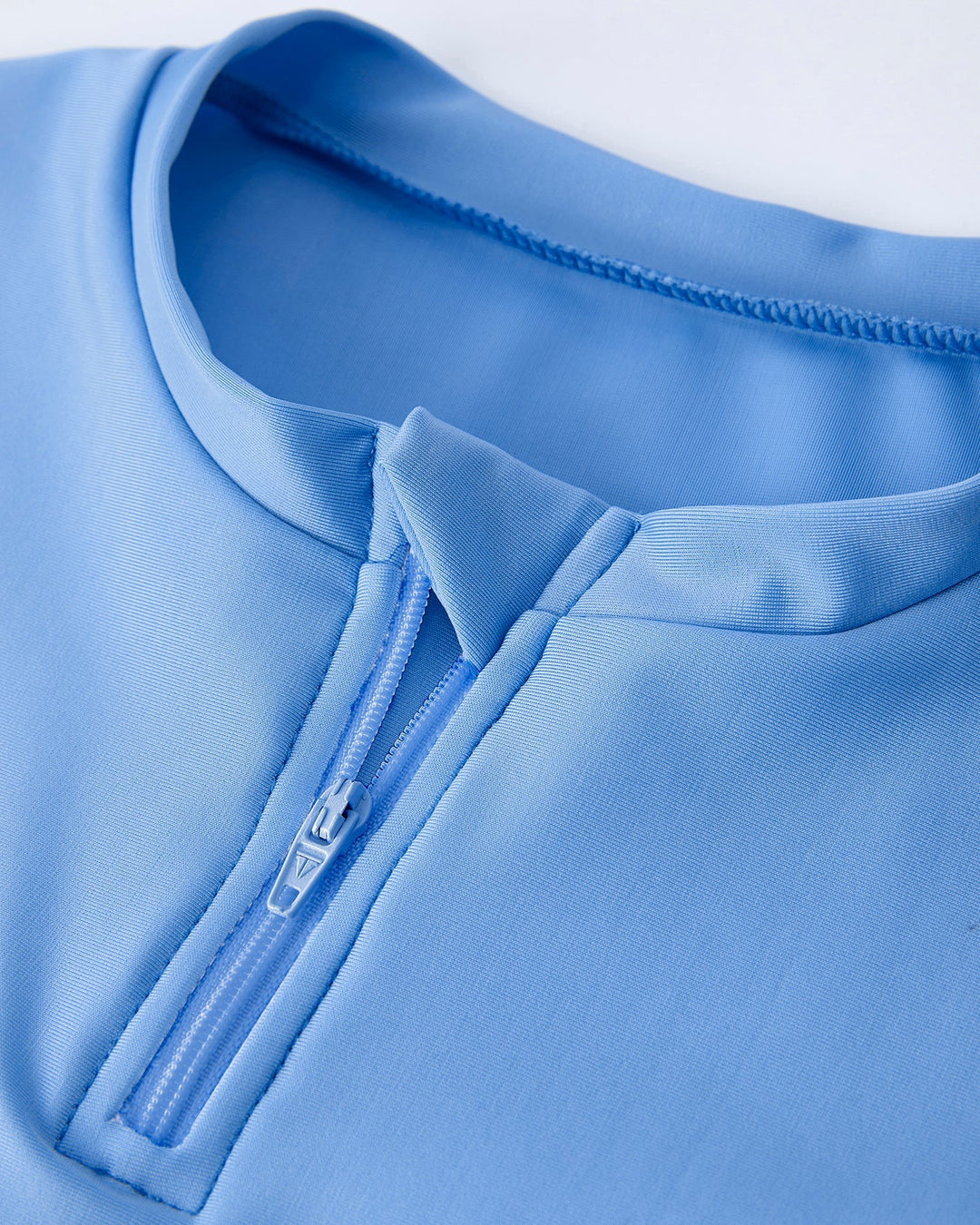 Close-up of a blue garment with a zipper detail on a light gray background