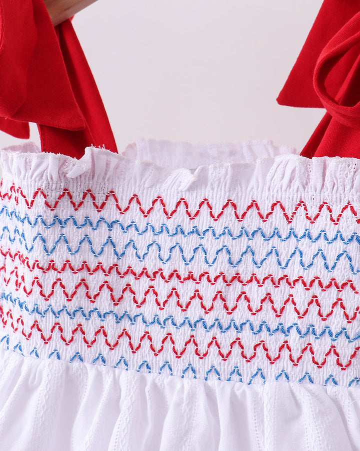 White dress with red and blue zigzag pattern on a plain background