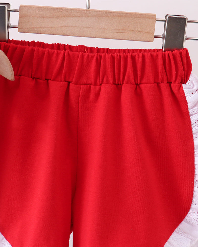 Red shorts with white lace trim on a hanger against a white background