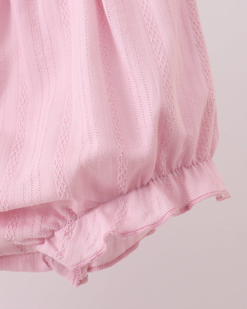 Close-up of a pink textured fabric with ruffled edge on a light background