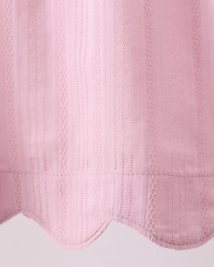 Close-up of a pink textured fabric with a scalloped edge on a light gray background